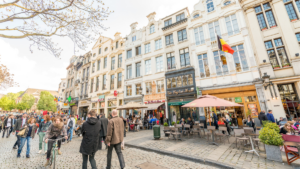 Rue animée du centre de Bruxelles avec commerces, terrasses et passants à quelques pas de la Grand-Place.