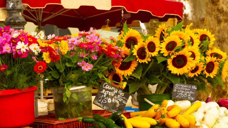 Étal coloré de fleurs et de légumes sur un marché, symbole des petits plaisirs qui peuvent aider à retrouver le moral.